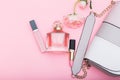 Perfume, lip gloss, lipstick and bag on a pink background