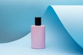 Perfume standing on blue paper background. pink bottle, Modern beauty trend