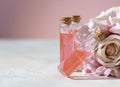 Perfumed Rose Water or essential oil in glass bottle and rose flower on a light background Royalty Free Stock Photo