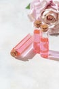 Perfumed Rose Water or essential oil in glass bottle and rose flower on a light background Royalty Free Stock Photo