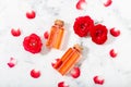 Perfumed Rose Water in glass bottle and small red roses with petals. Top view Royalty Free Stock Photo