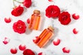 Perfumed Rose Water in glass bottle and small red roses with petals. Top view Royalty Free Stock Photo