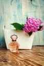 Perfumes and hydrangea in a white basket on blue wooden background