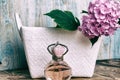 Perfumes and hydrangea in a white basket on blue wooden background