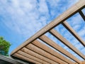 Pergola attached to house near roof gutter, sanded rafter ready for re-stain, wooden beams overhang post timber outdoor structure