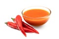 Peri peri chilli sauce in a glass bowl next to three red chillies isolated on white Royalty Free Stock Photo