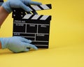 During the period of pandemics, hands in gloves concept of the film industry, a minimalistic composition on a yellow Royalty Free Stock Photo