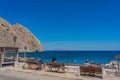 People looking to the black Perissa beach in Santorini from a bench