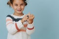Perky little girl in striped sweater counting on her fingers over blue