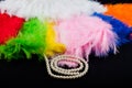 Perl necklace lay near soft colorful feathers on black fabric background
