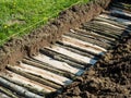 Permaculture trench building with logs of wood with grass side