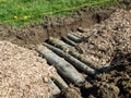 Permaculture trench with wood logs and shredded wood and grass in background