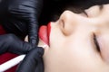 Permanent lip tattoo procedure the master prepares the lips for tattooing by outlining the contour with a white pencil