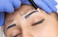 Permanent make-up for eyebrows of beautiful woman with thick brows in beauty salon.