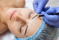 Permanent make-up for eyebrows of beautiful woman with thick brows in beauty salon. Closeup beautician doing tattooing eyebrow.