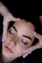 Permanent make-up of the eyebrows, close-up of the model's face, the master holds the eyebrows with his hands Royalty Free Stock Photo