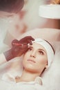 Permanent make-up wizard makes eyebrow correction procedure Royalty Free Stock Photo
