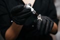 Permanent makeup artist pours brown pigment into the paint ring on finger in a black glove. Royalty Free Stock Photo