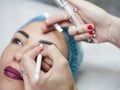 Permanent makeup beautician sketching eyebrows