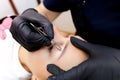 Permanent makeup master performs plucking of unnecessary hairs in the eyebrow area after the permanent makeup procedure