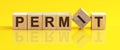 Permit word is made of wooden building blocks lying on the yellow table, concept Royalty Free Stock Photo