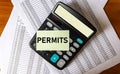 PERMITS word on sticker and calculator above permits and approved documents Royalty Free Stock Photo