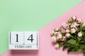 Perpetual calendar with date of February 14, bouquet of small roses on two-color background pink and green. Flat lay. Top view. St