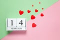 Perpetual calendar with date of February 14, red different-sized confetti hearts on two-color background pink and green. Flat lay Royalty Free Stock Photo