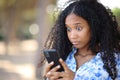 Perplexed black woman checking phone in a park Royalty Free Stock Photo