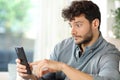 Perplexed man checking cell phone at home Royalty Free Stock Photo