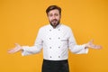 Perplexed smirked young bearded male chef cook or baker man in white uniform shirt posing isolated on yellow wall Royalty Free Stock Photo