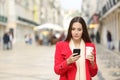 Perplexed woman using a smart phone in the street