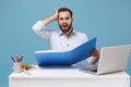 Perplexed young bearded man in light shirt sit work at desk with pc laptop isolated on pastel blue background Royalty Free Stock Photo