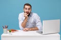 Perplexed young bearded man in shirt sit, work at desk with pc laptop isolated on pastel blue background. Achievement Royalty Free Stock Photo