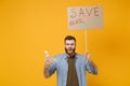 Perplexed young protesting man hold protest sign broadsheet placard on stick, plastic bottle isolated on yellow