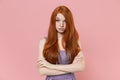 Perplexed young redhead woman girl in plaid dress posing on pastel pink wall background studio portrait. People