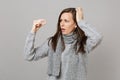 Perplexed young woman in gray sweater, scarf putting hand on head holding medication tablet, aspirin pill isolated on