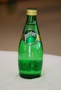 Perrier drinking sparkling water in green bottle