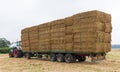 Tractor with a trailer in a field loaded with straw bales. UK