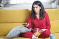 Persian woman at home watching TV and using remote control Royalty Free Stock Photo