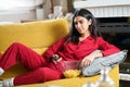 Persian woman at home watching TV and using remote control Royalty Free Stock Photo