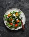 Persimmon, arugula, gorgonzola salad - delicious vegetarian seasonal snack, appetizer on a dark background, top view