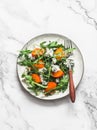 Persimmon, arugula, gorgonzola salad - vegetarian seasonal snack, appetizer on a light background, top view