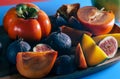 Persimmon, figs and mango on a wooden tray side view on blue Royalty Free Stock Photo