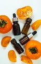 Persimmon fruit oil on a white background. Ripe persimmon fruits and extract in a cosmetic bottle with a dropper. Essential