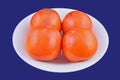 Persimmon fruit on white plate on blue background Royalty Free Stock Photo