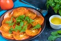 Persimmon Salad. Thinly sliced fruit slices lie on a brown plate, sprinkled with arugula leaves. Royalty Free Stock Photo