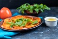 Persimmon Salad. Thinly sliced fruit slices lie on a brown plate, sprinkled with arugula leaves. Royalty Free Stock Photo