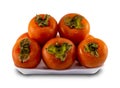 Persimmons stacked on a white plastic plate isolated on a white background Royalty Free Stock Photo