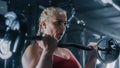 A Persistent Female Powerlifter Training by Lifting a Heavy Barbell in a Dark Gym. Portrait of a